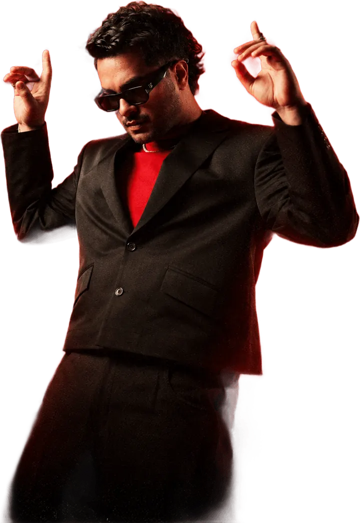 Asim Azhar in a black suit and sunglasses, hands raised